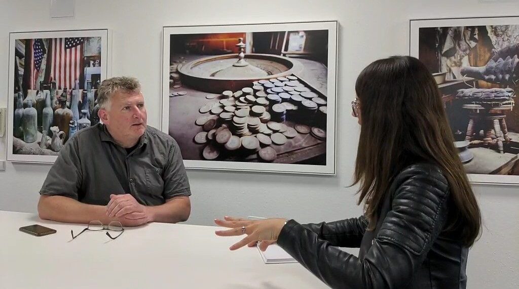 Fotograf Berthold Steinhilber und Consulting4IT Presseverantwortliche Linda Schmittner im angeregten Gespräch, im Hintergrund sieht mal gerahmte Bilder des Fotografen.