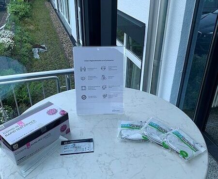 Beistelltisch mit Hygienehinweis, drei FFP2-Masken und eine Schachtel Corona-Tests.