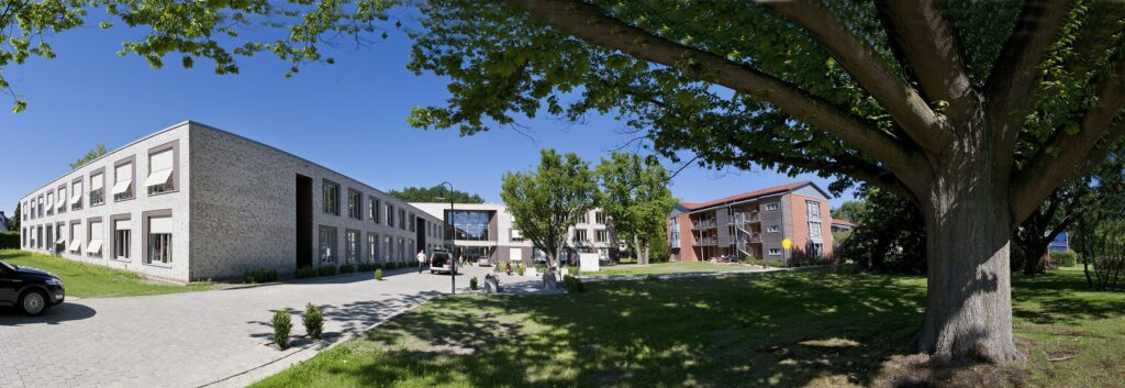 Haus 21 Via Vita und Da Vinci von Friedehorst mit gepflegtem grünen Garten und vielen Bäumen.