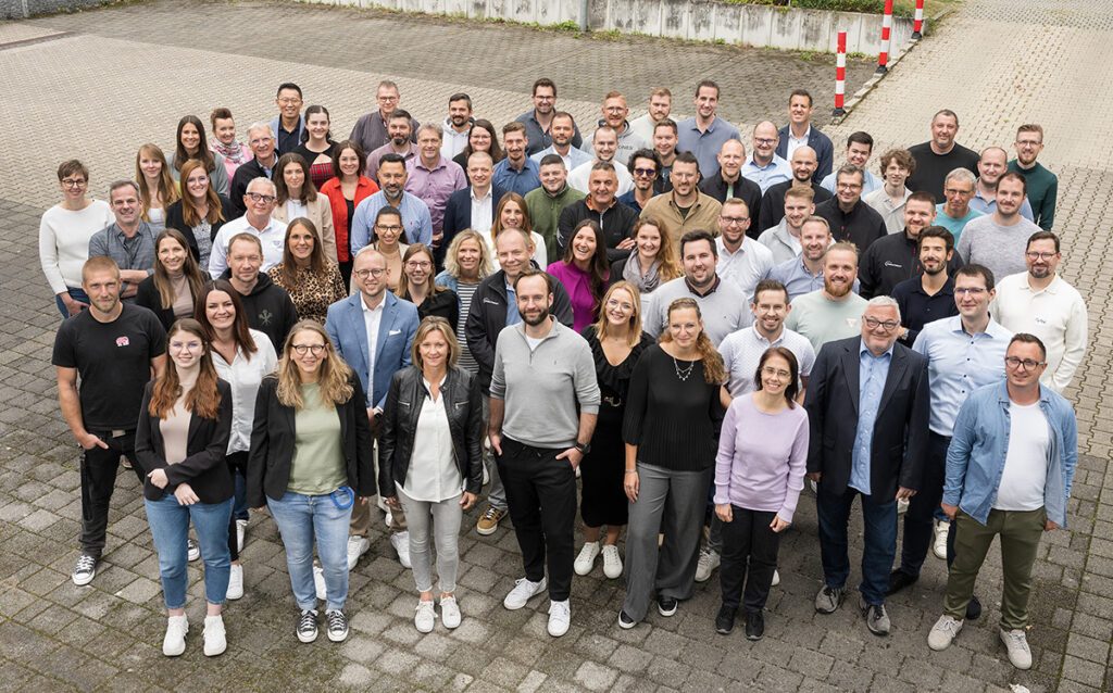 Gruppenbild der Consulting4IT Mitarbeiter auf dem Parkplatz.