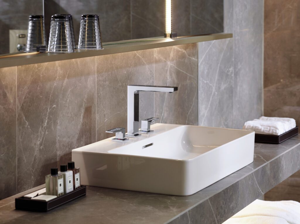 Ein modernes, weißes Waschbecken der Firma hansgrohe. Untertisch und Wand sind aus marmoriertem Stein.