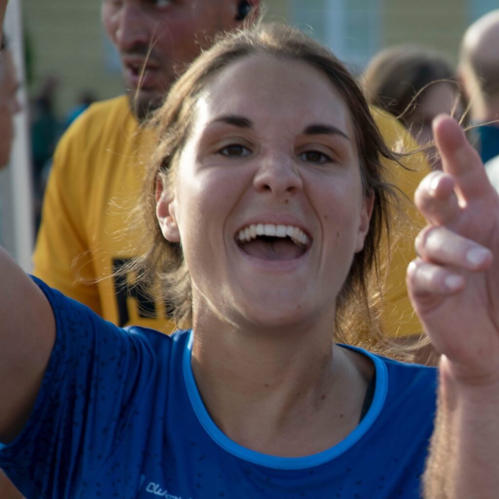 Consulting4IT Mitarbeiterin Lena Krech beim Zieleinlauf des B2Run Karlsruhe 2022. Sie trägt ein blaues Laufshirt und jubelt in die Kamera.