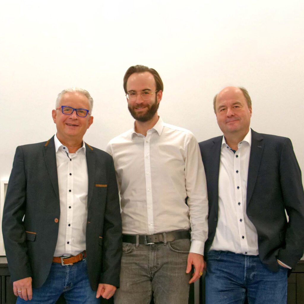 Die drei Geschäftsführer der Consulting4IT - Mirko Oesterhaus, Patrick Hild und Christian Müller - posieren lächelnd vor einem weißen Hintergrund.