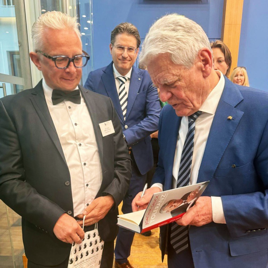 Bundespräsident a.D. Joachim Gauck signiert ein Buche für Mirko Oesterhaus, der erwartungsvoll daneben steht.