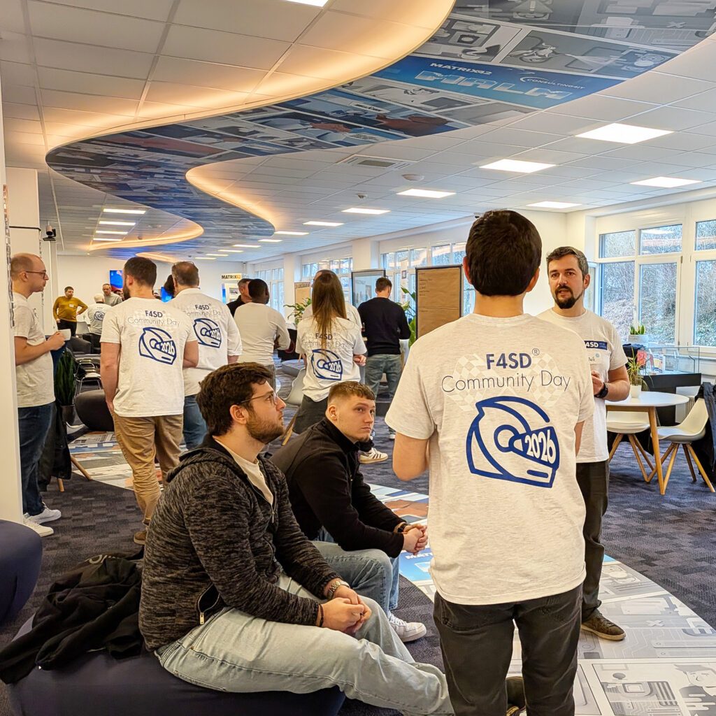 Networking: Many people in the room; some are talking, others are listening, and some are wearing F4SD T-shirts.